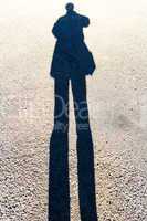 Elongated Shadow of a Person Standing on the Road