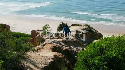 Man Climb on a Cliff Above the Ocean, sunny day