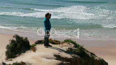 Man Climb on a Cliff Above the Ocean, sunny day