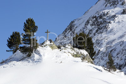Cross in snowy mountain landscape