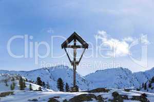 Cross in snowy mountain landscape