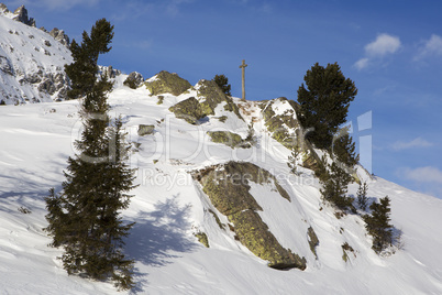 Cross in snowy mountain landscape