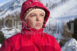 Woman with red jacket looks into the distance in the mountains