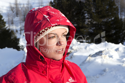 Woman with red jacket looks into the distance in the mountains