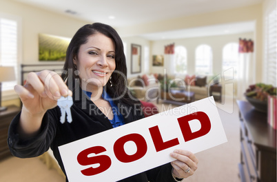 Hispanic Woman with Keys and Sold Sign in Living Room