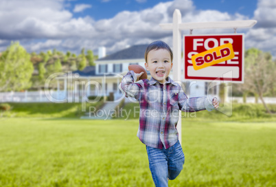 Boy Playing Ball in Yard Near Sold Real Estate Sign