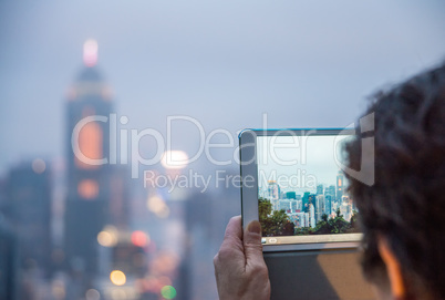 Tourist capturing Hong Kong night skyline with tablet