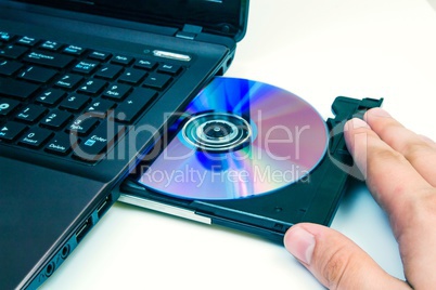 Man insert compact disc from laptop