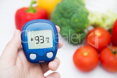 Diabetes doing glucose level test. Vegetables in background