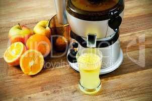Juicer and orange juice on wooden background