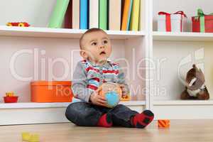 Baby Kind beim Spielen mit Ball und schaut nach oben