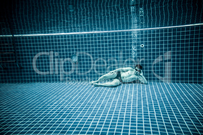 Persons lies under water in a swimming pool