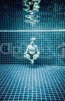 Man under water in a swimming pool to relax in the lotus positio