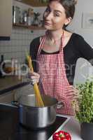 Frau beim Kochen von Spaghetti in der Küche