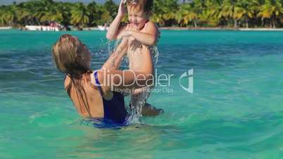 Mother and son playing in clear sea water