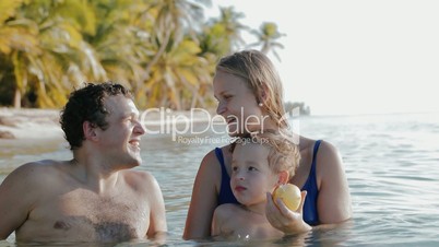 Family of three relaxing in sea water in tropics