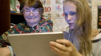 Young and senior woman looking through photos on pad