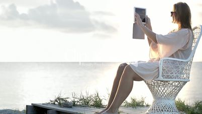 Woman near the sea making photos using pad