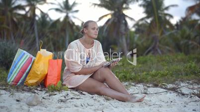 Woman after shopping using tablet PC on the beach