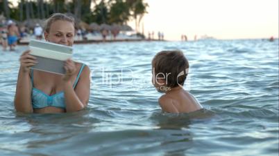 Mother with pad making photo or video of son in water