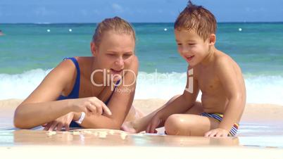 Boy watching mother drawing on sand