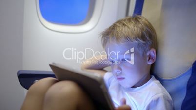 Bored or tired boy in plane using tablet computer