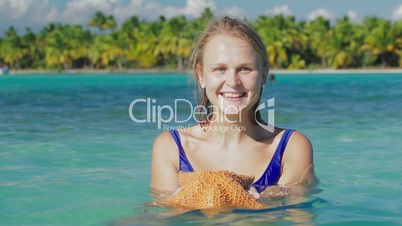 Smiling woman in sea water with starfish