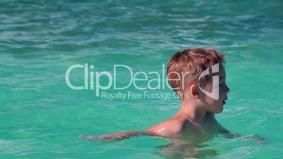 Little boy bathing in clear blue sea