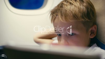 Little boy using tablet computer during flight