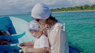 Mother and son using pad while traveling by sea