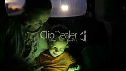 Little boy using tablet pc during car travel  at night
