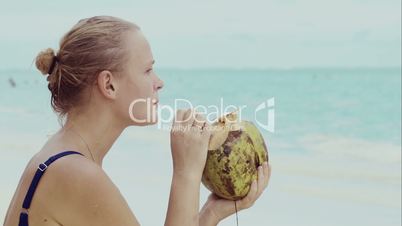 Woman on the beach drinking from coconut