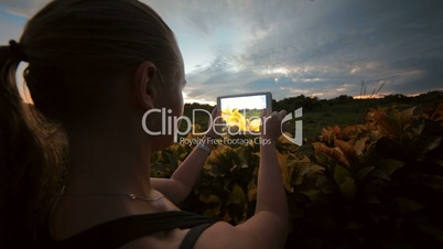 Woman using tablet PC to take photos of nature scenes
