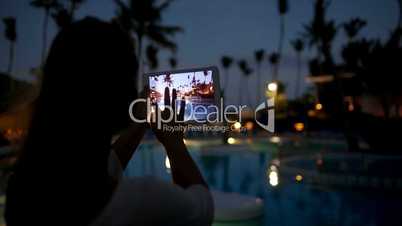 Woman using pad to take photos on tropical resort