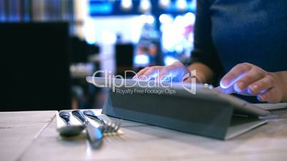 Woman typing message or e-mail on pad in cafe