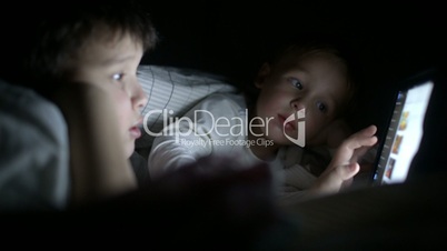Two little boys try to watch the film at night using tablet