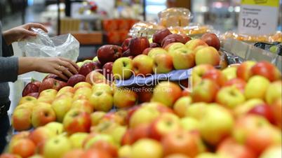 Woman in the supermarket putting apples plastic bag