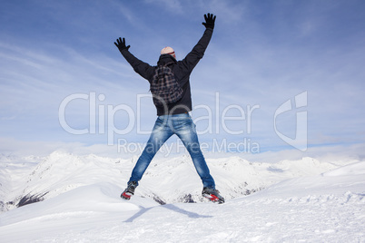 Young man jumps for joy in the snowy mountains