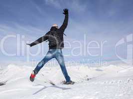 Young man jumps for joy in the snowy mountains
