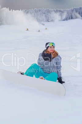 Junges Mädchen in Übergröße sitzt mit Ihren Snowboard im Schnee