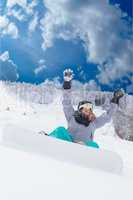 Junges Mädchen in Übergröße sitzt mit Ihren Snowboard im Schnee und freut sich