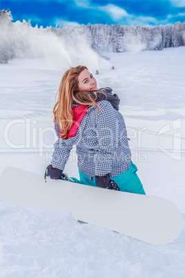 Junge mollige Frau mit einem Snowboard auf der Skipiste , kniend im Schnee