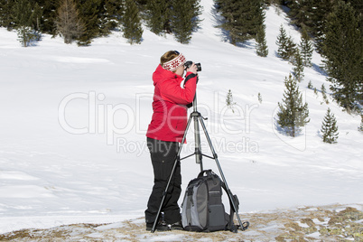 Female photographer takes pictures in winter landscape