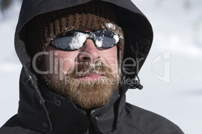 Young man with snow in his face looks into the distance
