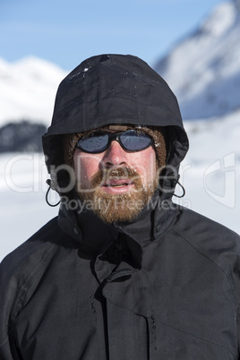 Young man in snowy mountain landscape looks into the camera