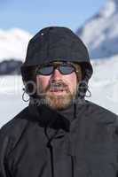 Young man in snowy mountain landscape looks into the camera