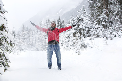 Happy young man with snow glasses throws up snow