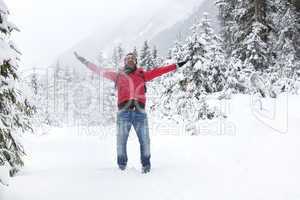 Happy young man with snow glasses throws up snow