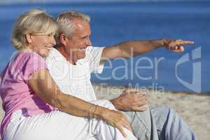 Senior Couple Sitting on Beach Pointing