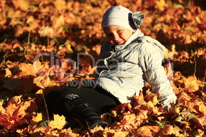 little girl laying in yellow leaves